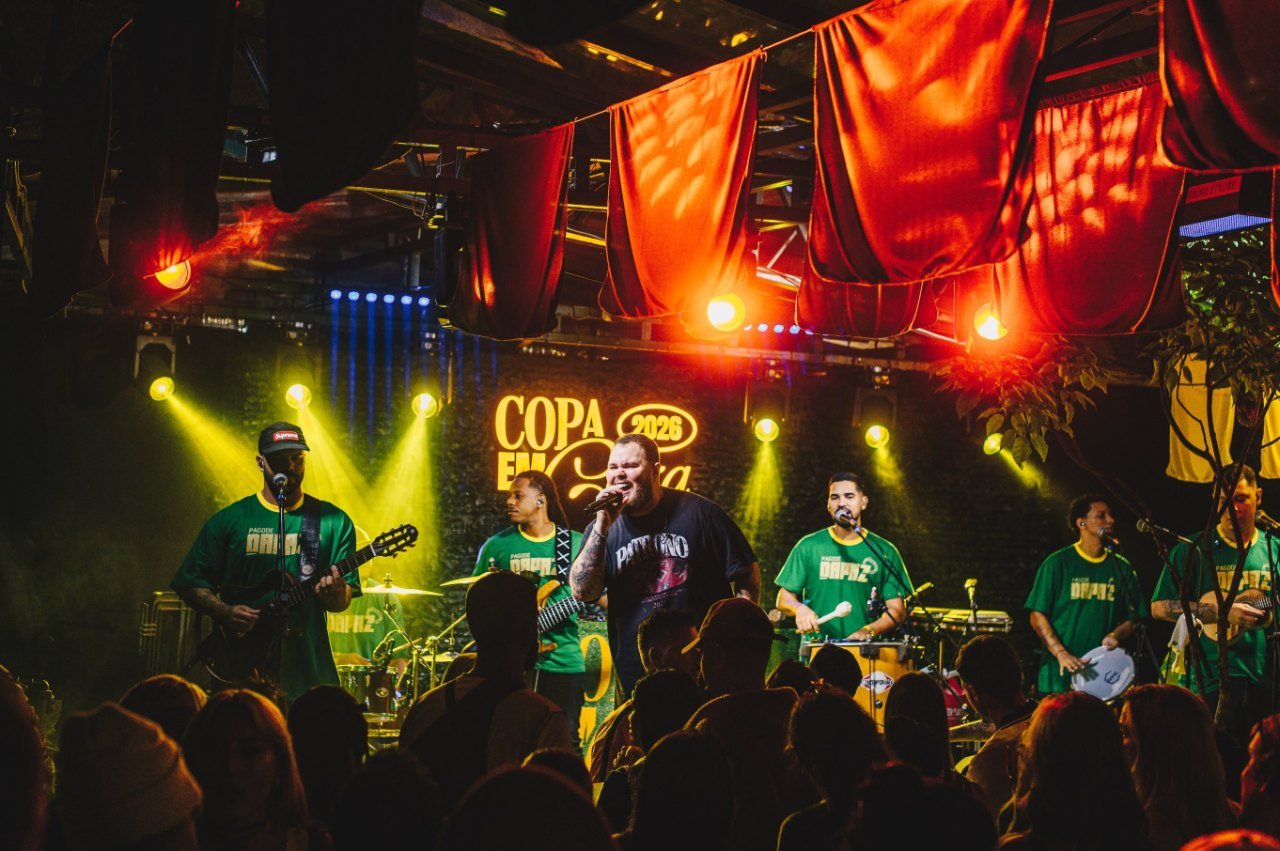 Banda ao vivo no palco da Caza Lagoa, com luzes vermelhas e público